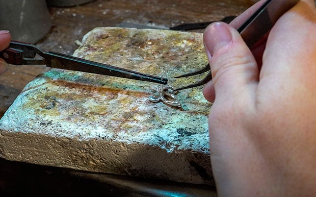 Proceso creativo en taller de joyería contemporánea artesana: manos artesanas creando un pendiente único de Emeki Joyas