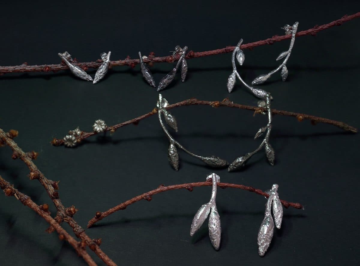 Conjunto de pendientes maxi, medium y txiki de plata de la colección Brotes de haya, brotes de Vida, presentados sobre ramas en fotografía de estudio. Joyería contemporánea artesanal de Emeki Joyas.