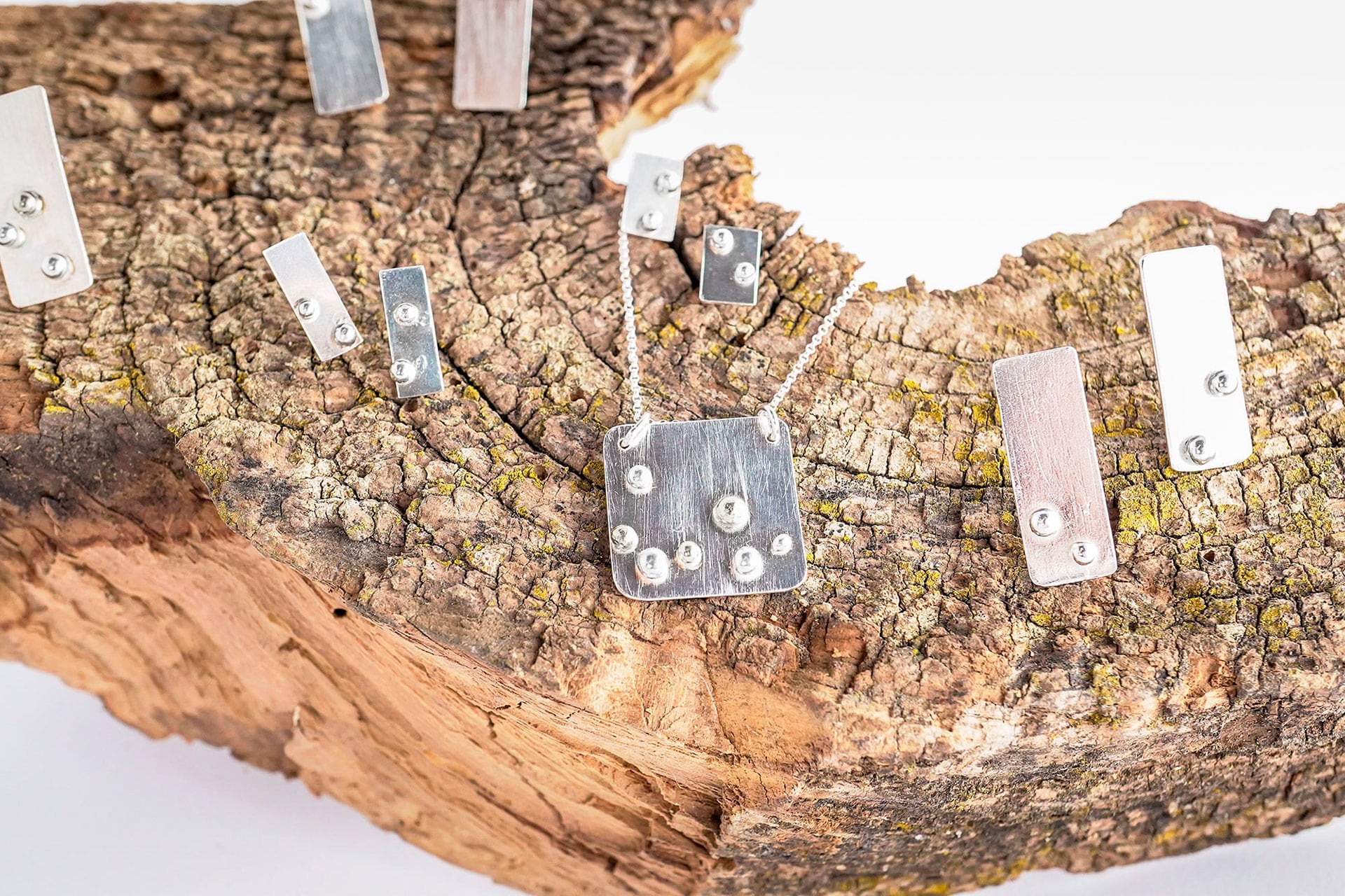 Detalle de las piezas de la colección Xirimiri, con láminas geométricas y pequeñas esferas que evocan gotas de lluvia apoyadas sobre el cristal de una ventana.